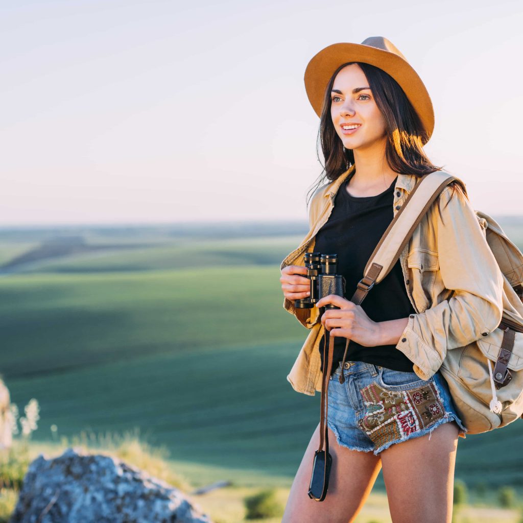 smiling-female-hiker-holding-binocular-min